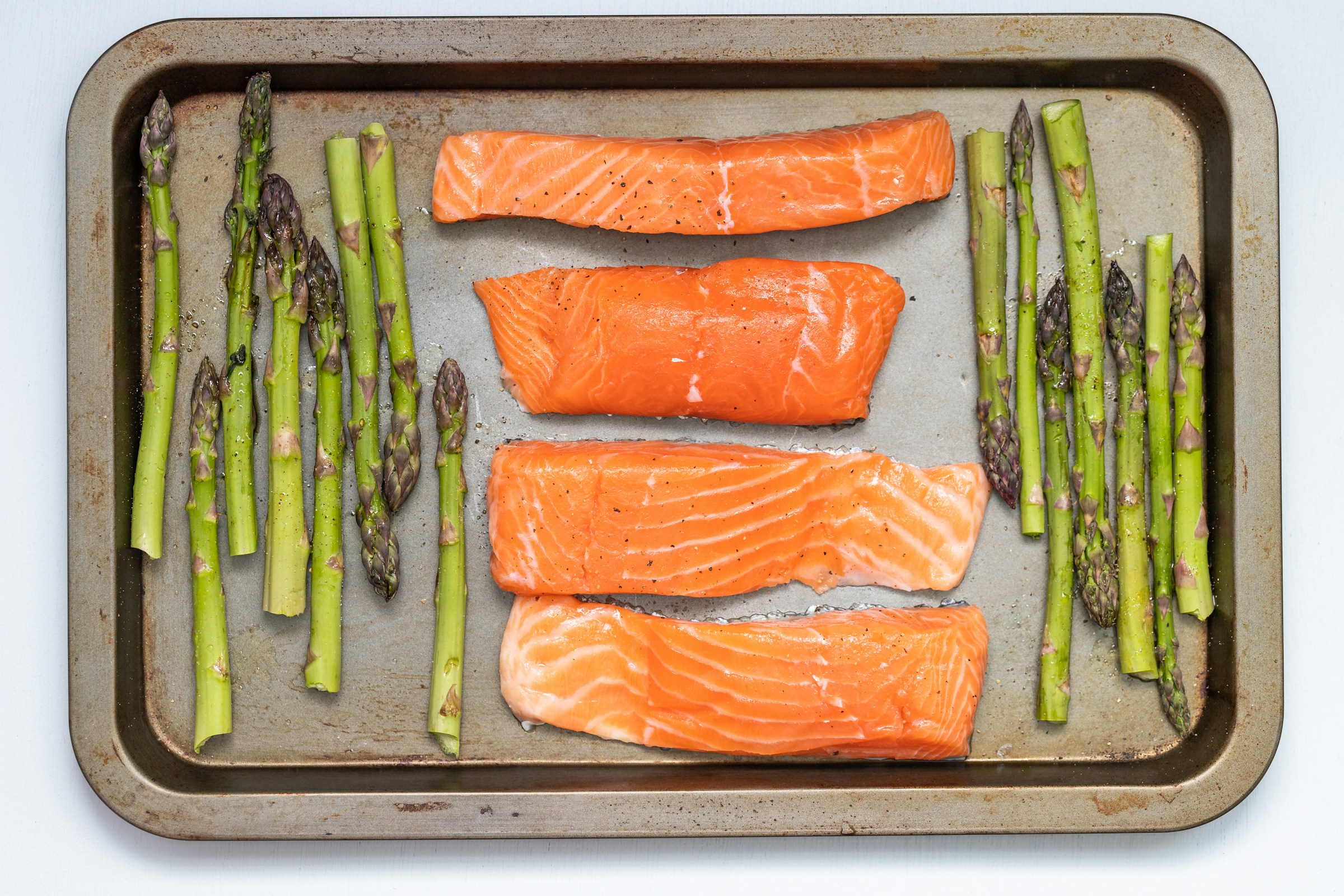 Raw salmon on sheet tray with asparagus